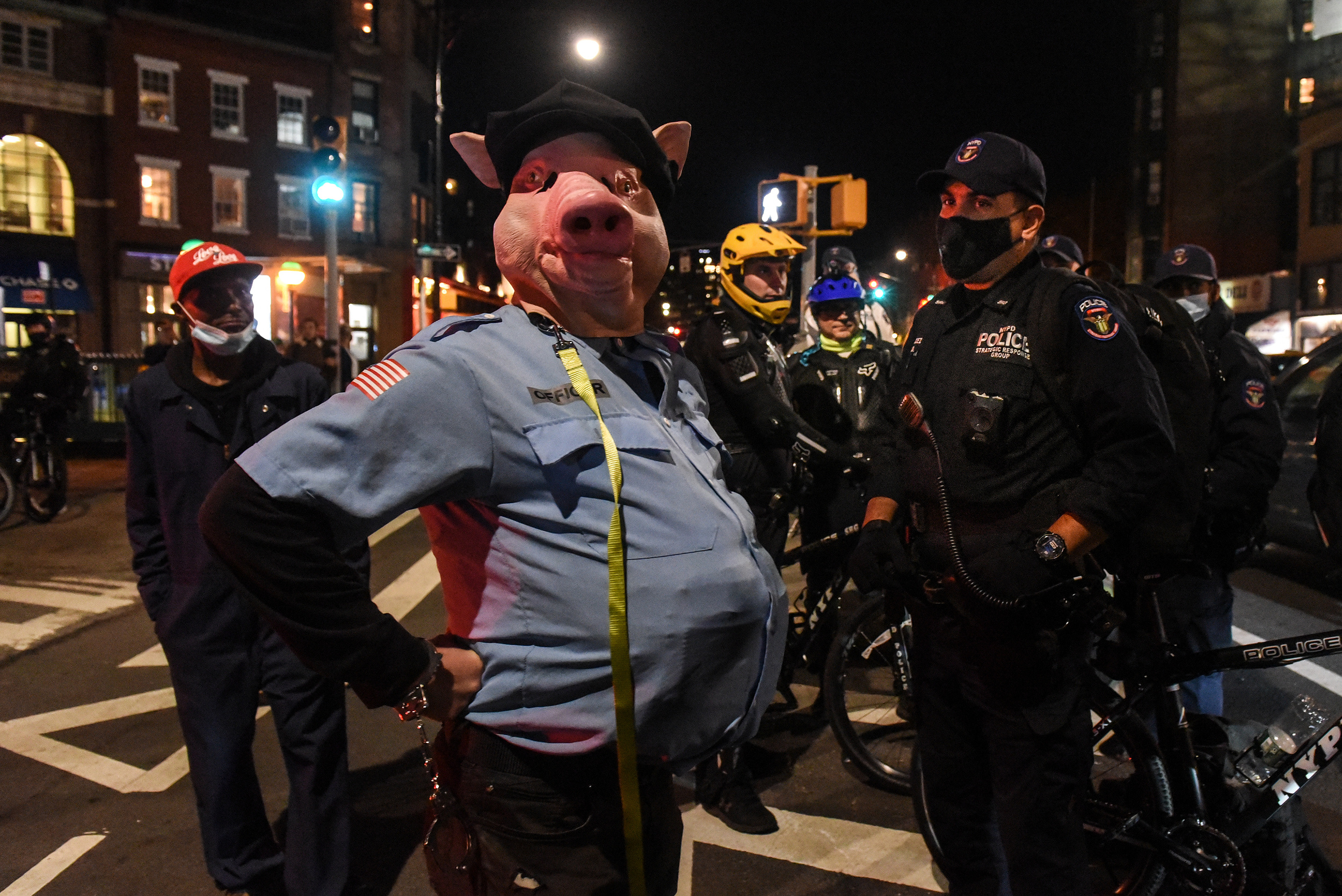 A demonstrator wears a pig mask and stand near to New York Police Department (NYPD) officers at a protest during the 2020 Presidential election in New York, U.S., on Thursday, Nov. 5, 2020. Joe Biden stood on the brink of claiming the presidency from Dona